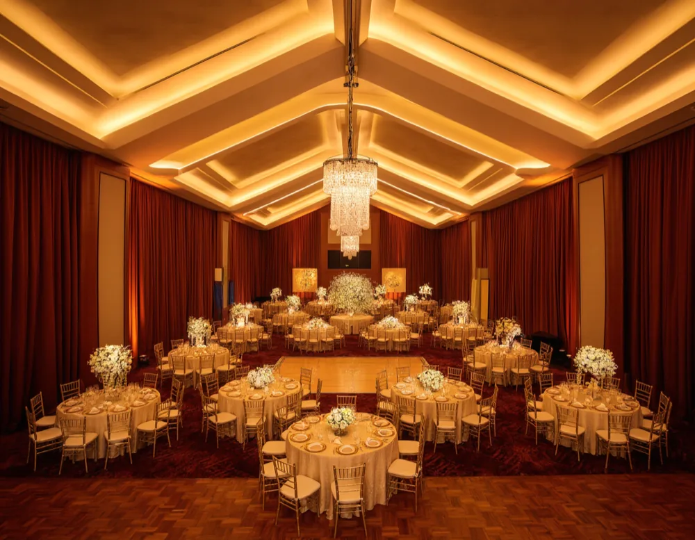 The main hall dressed for a wedding, crimson drapes and a glowing LED stage wall